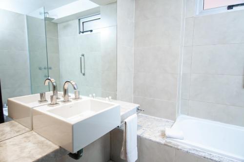 a white bathroom with a sink and a tub at Amérian Tucuman in San Miguel de Tucumán