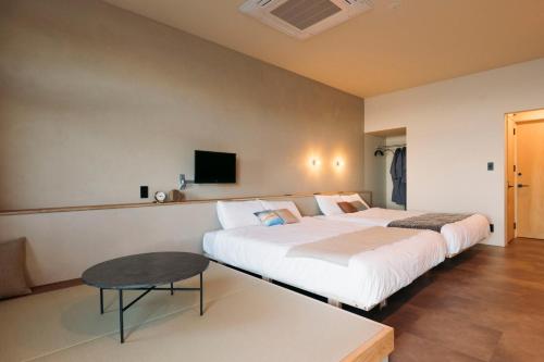 een hotelkamer met 2 bedden en een tafel bij Nagasaki House Burabura in Nagasaki