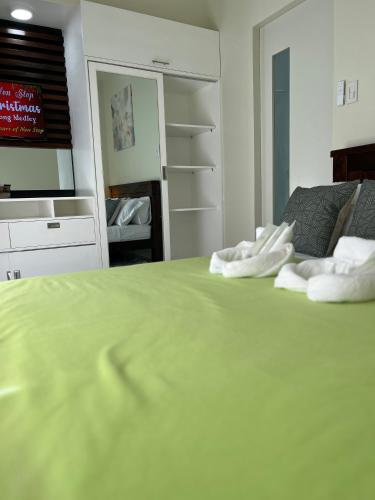 a bedroom with a green bed with towels on it at Brenthill Baguio condo unit near SM baguio in Baguio