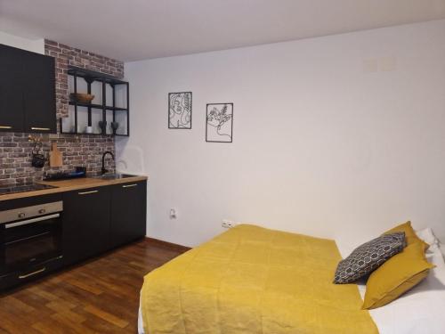 1 dormitorio con 1 cama con manta amarilla en Sunny studio with nice mountain view from terrace, en Jesenice