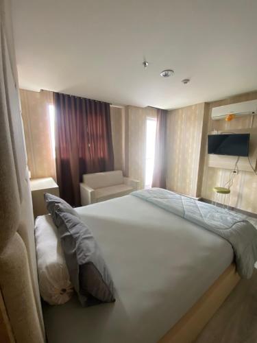 a bedroom with a large white bed and a couch at apartemen bintaro icon in Pondokaren
