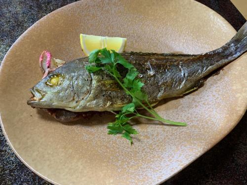 a fish on a plate with a garnishment at HOTEL LT Kitchen Yugawara in Yugawara