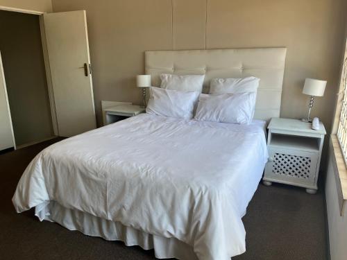 een slaapkamer met een groot wit bed en 2 nachtkastjes bij Executive suite@Lofts in Pretoria