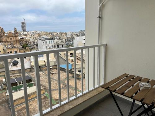 einen Balkon mit einer Bank und Stadtblick in der Unterkunft F10 Modern and Bright Apartment in Malta in Msida