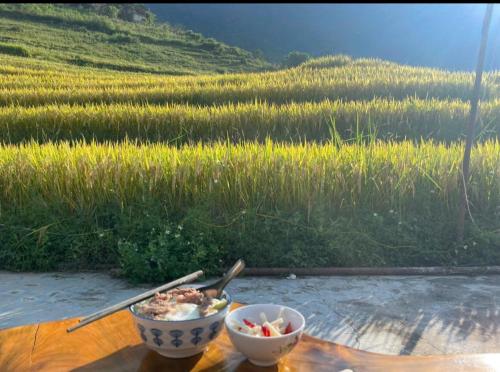 uma tigela de comida numa mesa em frente a um campo em Hmong Wooden Home em Sa Pa