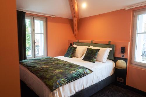 - une chambre avec un lit aux murs orange et des fenêtres dans l'établissement Maison Bayard, à Montpellier