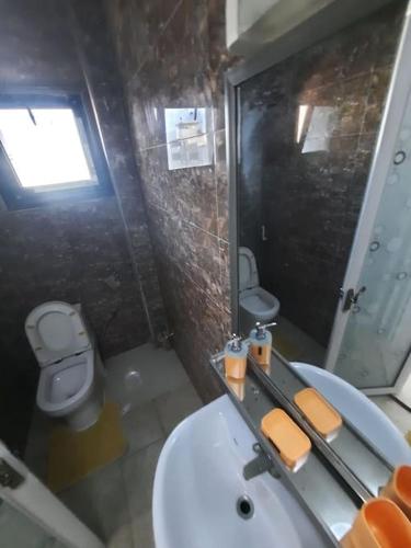 een badkamer met een wastafel, een toilet en een spiegel bij Appartement Paisible in Dakar