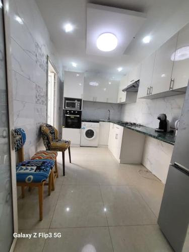 een grote keuken met witte kasten en apparaten bij Appartement Paisible in Dakar