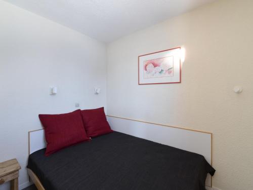 - une petite chambre avec un lit et des oreillers rouges dans l'établissement Appartement confortable au pied des pistes avec balcon | 5 pers - FR-1-181-2031, à La Plagne Tarentaise