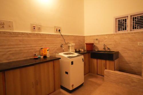 a small kitchen with a sink and a small refrigerator at Palace Hostel by Borrbo in Mysore