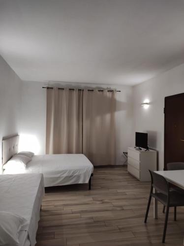 a bedroom with two beds and a desk and a tv at Dalmati House San Lorenzo in Rome