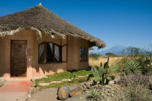 a small house with a thatched roof in a field at Kia Lodge in Arusha