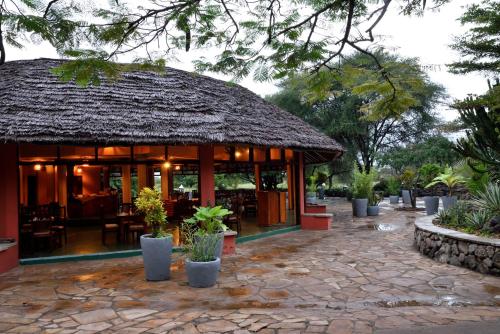 a restaurant with a thatched roof and a patio at Kia Lodge in Arusha