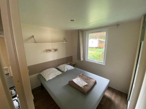 - un petit lit dans une petite chambre avec fenêtre dans l'établissement MOBIL HOME Clim BOOFZHEIM 6 PERSONNES 3 CHAMBRES LE RIED 3 ETOILES PROCHE EUROPA PARK, à Boofzheim