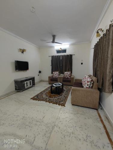 S A Villa في حيدر أباد: غرفة معيشة مع كنب وتلفزيون بشاشة مسطحة