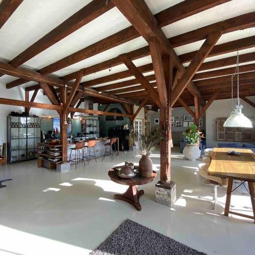 a large living room with wooden ceilings and a table at Farmhouse bohemian style close to Amsterdam in Waverveen