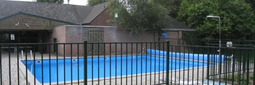 une piscine bleue derrière une clôture noire dans l'établissement Camping Leef!, à Melderslo