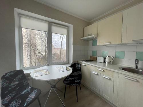キーウにあるАпартаменты на Нежинской 29Г недалеко от Индустриального мостаのキッチン(テーブル、椅子2脚付)、窓が備わります。