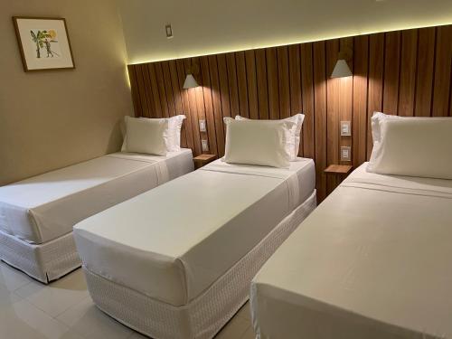 two beds in a hotel room with white pillows at Principe do Mutá Hotel Design in Santa Cruz Cabrália