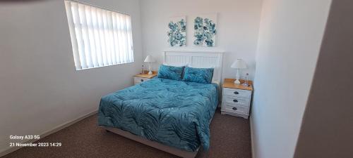 a bedroom with a bed with a blue comforter at Top Deck in Struisbaai