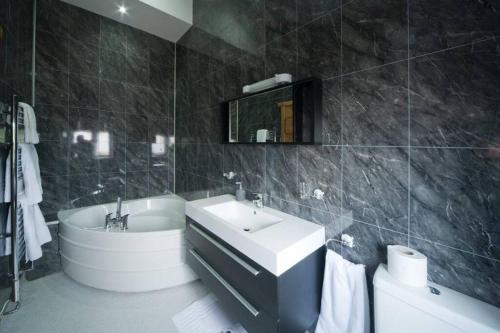 a bathroom with a sink and a tub and a toilet at Oak Barn in Brecon