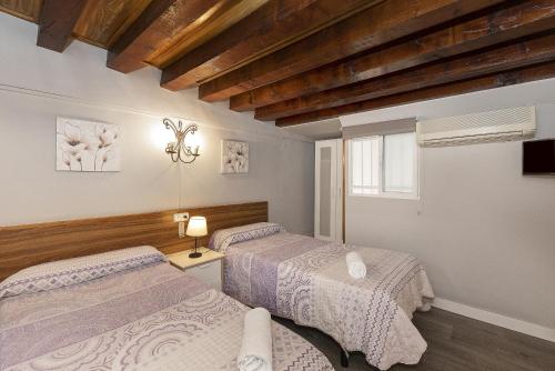 1 dormitorio con 2 camas y ventana en Pensión Riosol, en Sevilla