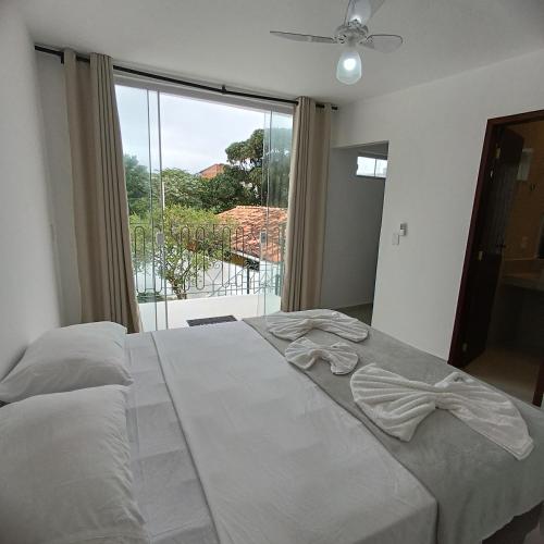 a bedroom with a large bed with a large window at Ressurgência loft in Arraial do Cabo