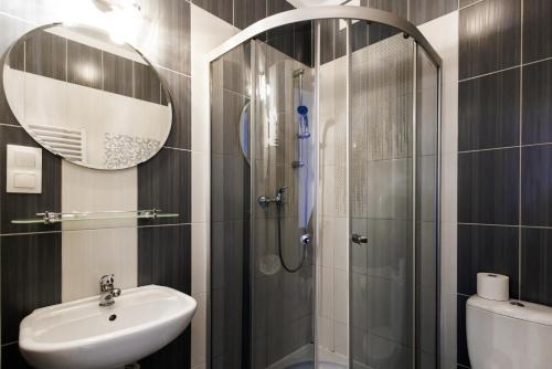 La salle de bains est pourvue d'une douche, d'un lavabo et d'un miroir. dans l'établissement Pensjonat Lawendowy Zakątek, à Zabłudów