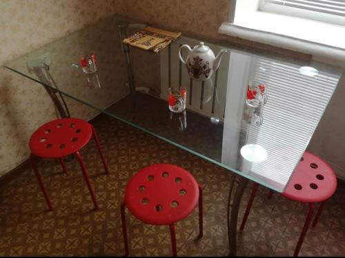 a glass table with two red chairs and a glass table with a glass top at VIP apart 401 in Tbilisi City