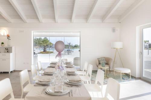 una sala da pranzo bianca con un lungo tavolo e sedie bianche di Hotel S'arena Beach a La Caletta