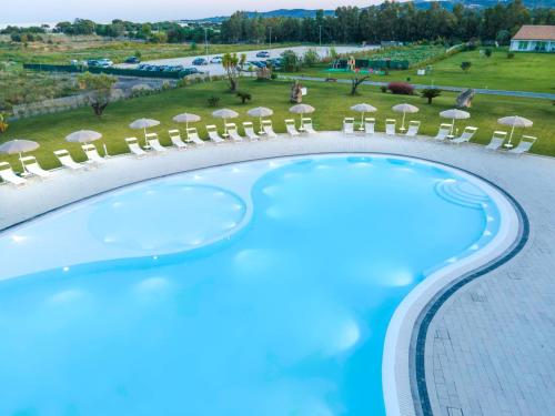 - une vue sur la piscine bordée de chaises et de parasols dans l'établissement Hotel S'arena Beach, à La Caletta