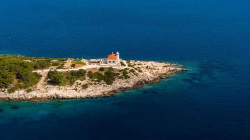 an island in the ocean with a lighthouse on it at Luxury seafront Villa Lighthouse Ligero on Host island - Vis island in Vis
