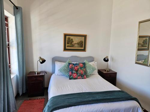 a bedroom with a bed with pillows and two lamps at Kelkiewyn Guesthouse Caledon in Caledon