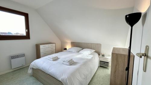 une chambre avec un lit blanc avec des serviettes dessus dans l'établissement L'Estran 43, au Crotoy