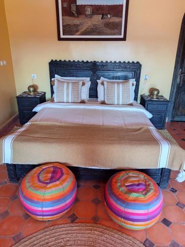 a bedroom with a large bed with two ottomans at Petit paradis in Sidi Bibi