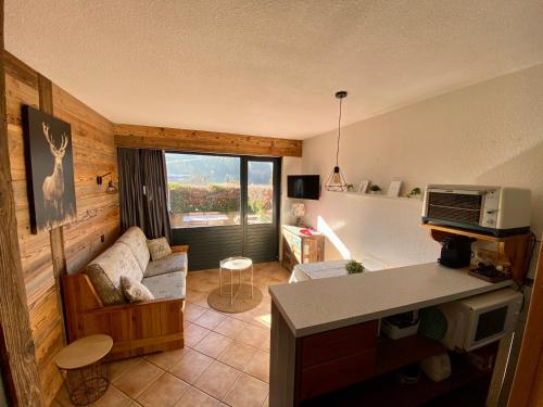 a living room with a couch and a window at Studio 2/4 personnes - Centre village in La Clusaz