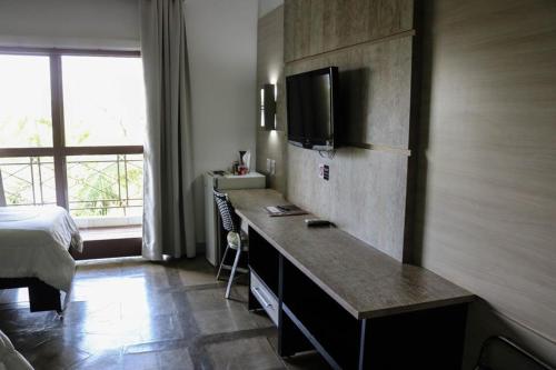 1 dormitorio con 1 cama y escritorio con TV en ARAGUAIA HOTEL, en Barra do Garças