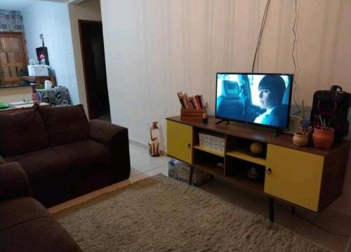 uma sala de estar com uma televisão e um sofá em Casa de praia em Unamar com piscina em Cabo Frio
