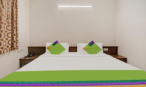 um quarto com uma cama branca com lençóis e almofadas coloridos em Hotel Prime Pavilion-MG ROAD em Bangalore