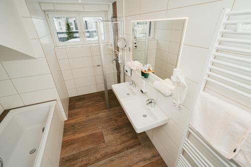 La salle de bains blanche est pourvue d'un lavabo et d'un miroir. dans l'établissement Apparthotel Samson, à Obertauern