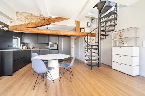 a kitchen with a table and chairs and a spiral staircase at Superbe Appartement Intramuros in Avignon