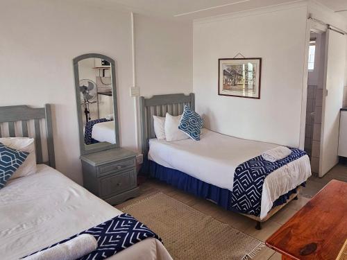 a bedroom with two beds and a mirror at Kelkiewyn Guesthouse Caledon in Caledon
