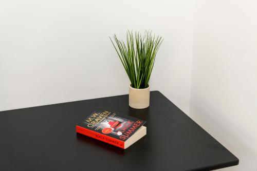 a black table with a book and a potted plant at Asher Suite by Koya Homes - 2-Bedroom Home, Downtown Barry, Free Parking in Barry