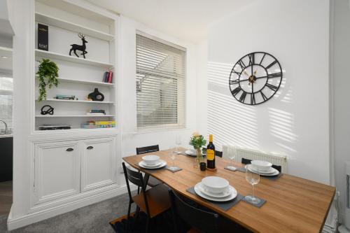 a dining room with a table and a clock on the wall at Asher Suite by Koya Homes - 2-Bedroom Home, Downtown Barry, Free Parking in Barry