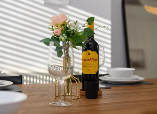 a bottle of wine and a vase of flowers on a table at Asher Suite by Koya Homes - 2-Bedroom Home, Downtown Barry, Free Parking in Barry