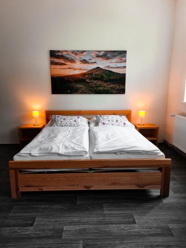 a bedroom with a bed with two lamps and a painting on the wall at Apartmány u Maxíků in Horní Maršov