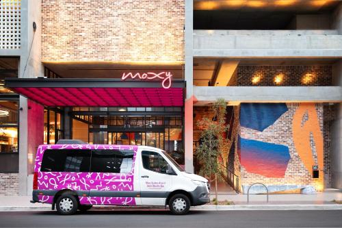 un furgone bianco parcheggiato di fronte a un edificio di Moxy Sydney Airport a Sydney
