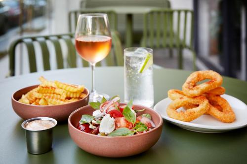a table with two bowls of food and a glass of wine at Moxy Sydney Airport in Sydney