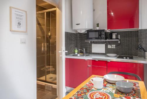 una pequeña cocina con armarios rojos y una mesa en Résidence Clignancourt, en París