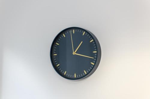a black clock with gold hands on a white wall at Asher Suite by Koya Homes - 2-Bedroom Home, Downtown Barry, Free Parking in Barry